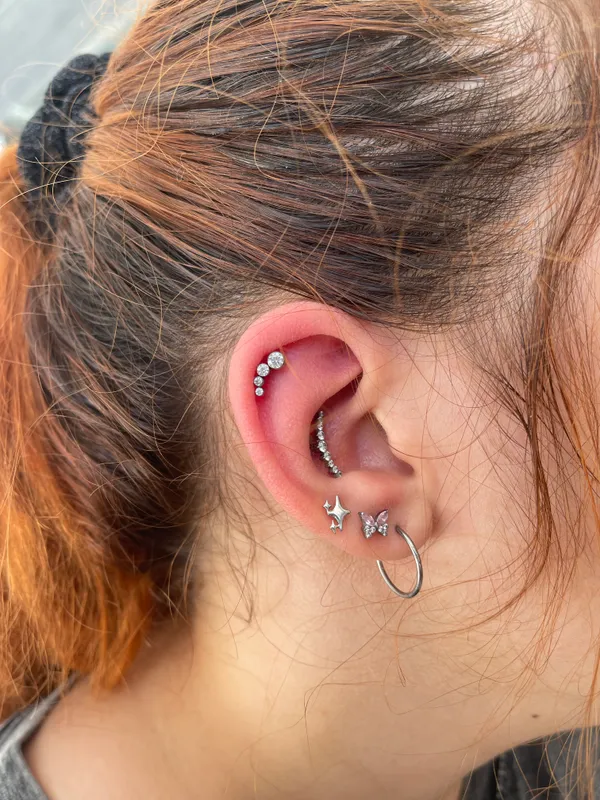 Piercings conch e helix na orelha com joias em titânio, feitos no Lonely Hearts Club Tattoo, Torres Vedras